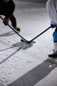 opponents holding hockey sticks beside each other