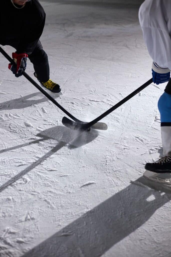 opponents holding hockey sticks beside each other
